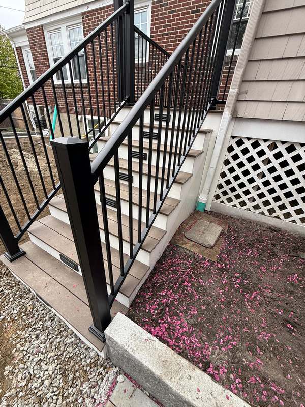 Deck stairs and railing beside a brick exterior